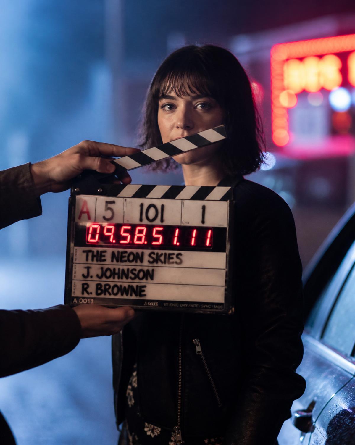 Clapperboard snapping on a neon-lit night set